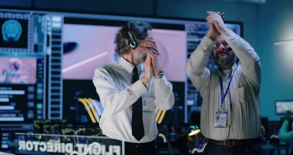 Middle Aged Operators Watching and Celebrating Mission Success alt