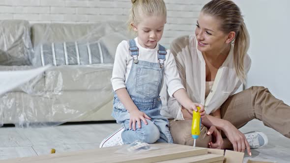 Girl Assembling Furniture with Toy Screwdriver alt