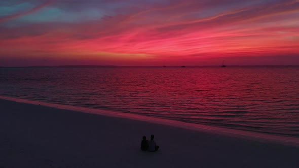 Aerial: flying over tropical beach and sea at sunset alt