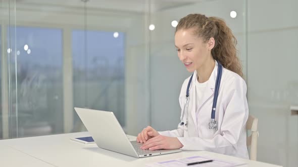Cheerful Young Female Doctor Doing Video Chat on Laptop alt