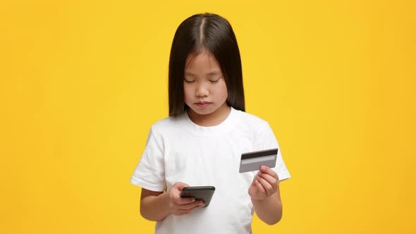 Little Japanese Girl Shopping Using Smartphones And Credit Card Studio alt