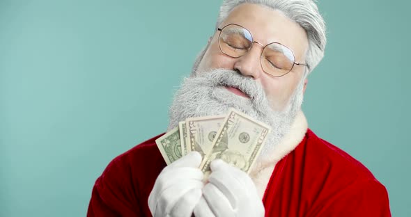 Joyful Santa Claus on a Blue Background Holds Money Dollars in His Hands