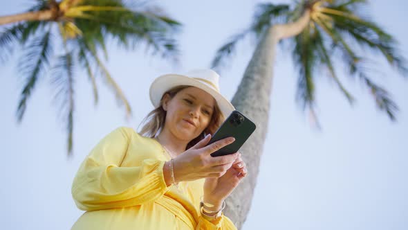 Happy Caucasian Smiling Woman Holding Cell Phone Using Smartphone Hawaiian Beach alt