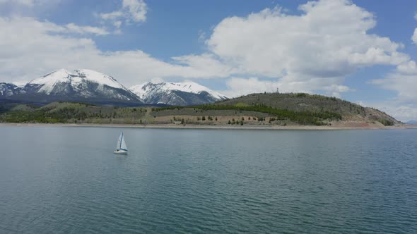 Aerial Flyby Shot of a Lone Sailboat on a Beautiful Mountain Lake in Colorado (Dillon Reservoir) alt