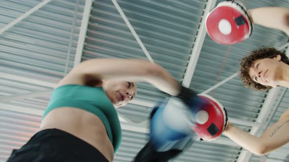 Low Angle Shot of Young Woman Practising Boxing Moves with Female Instructor Indoors in Gym alt