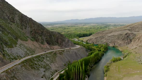 Aerial view of mountain river with the dam and road with card passing by alt