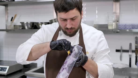 Male Pastry Chef Who Uses a Washcloth to Apply Shiny Candurin to a Mold for Chocolate Spheres alt