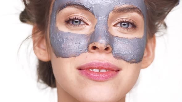Young Caucasian Lady with Facial Mask Looking at Camera Over White Background alt