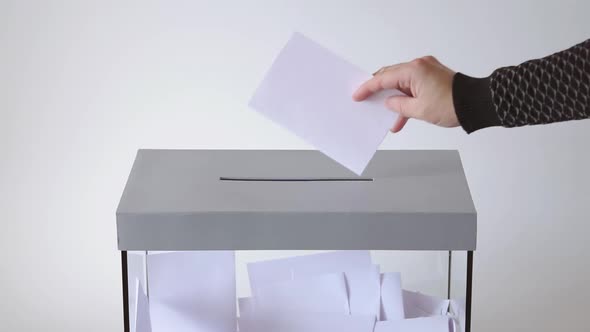 Close Up Of Hands Putting Ballot In Glass Box