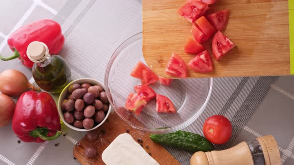 Greek Salad Preparation Series Concept  Woman Pouring Sliced Tomatoes Into a Bowl alt