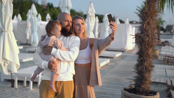 Family Vacation on a Tropical Beach Father Mother and Daughter are Standing on the Sand and Making a alt