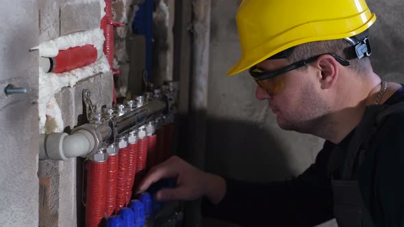 A Male Plumber Sets Up Heating in a Newly Built House alt