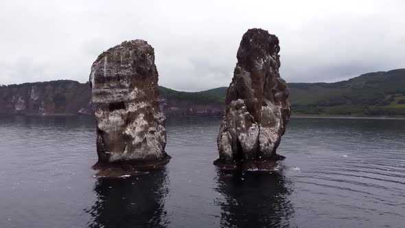 two rocks in the ocean with flying seagulls