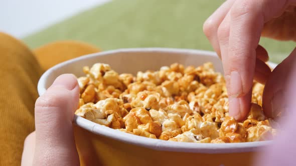 Close Up View on Female Hand Holding a Popcorn While Watching a Movie in the Living Room alt