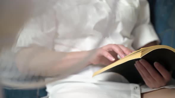 a woman reads an interesting book sitting in front of a fan. close-up of a hand and a book.