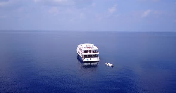 Natural fly over clean view of a white sand paradise beach and blue water background in high resolut alt