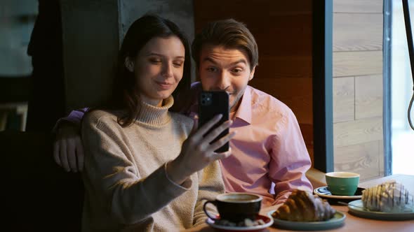 Happy Cute Couple Having Videochat Via Smartphone in Coffee Shop Concept of Keeping in Touch