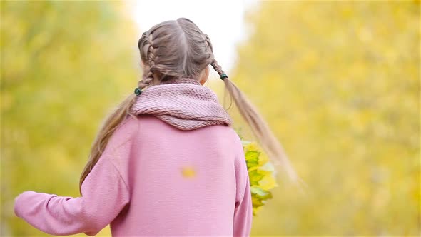 Happy Kid with Yellow Leaves Outdoors in Fall alt