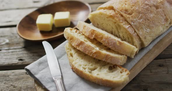 Video of bread on chopping wooden board on wooden worktop alt