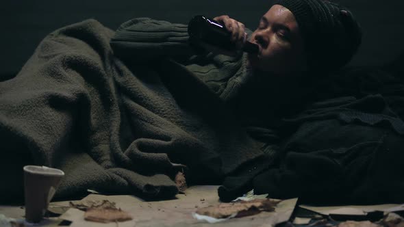 Pity Homeless Person Lying on Floor and Drinking Beverage, Alcohol Addiction alt