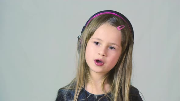 Pretty Smiling Cild Girl Listening to Music in Big Pink Earphones alt