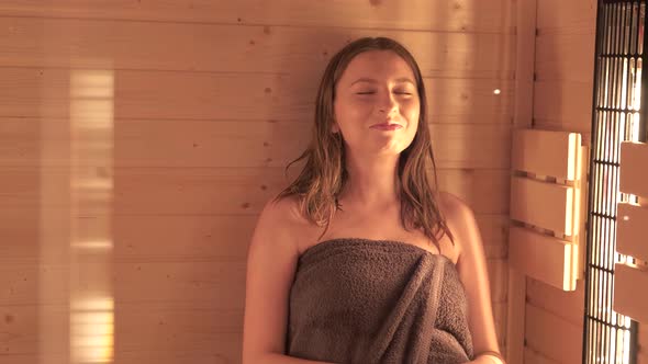 Young Girl Sitting in the Sauna with Closed Eyes