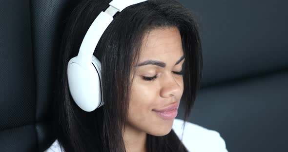 Beautiful african american woman relaxing and listening to music using headphones. alt