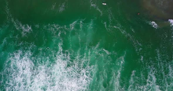 Big waves on the shore near the sandy beach. Top view, shooting from a drone.