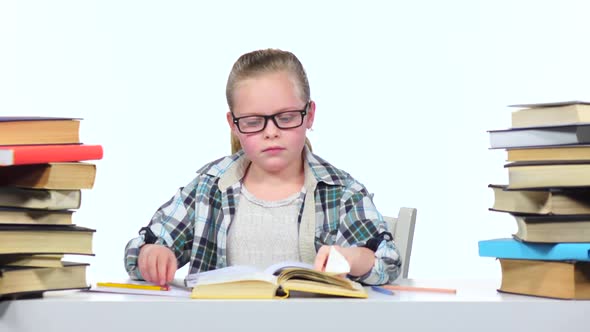 Girl Sits at the Table Leafing Through the Book. White Background alt