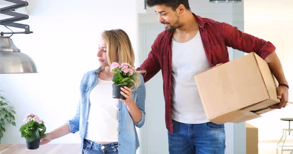 Young Couple Moving in New Home and Unpacking Carboard Boxes