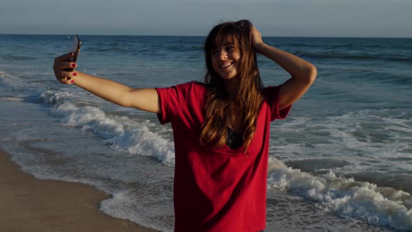 Attractive woman taking a selfie at the beach alt