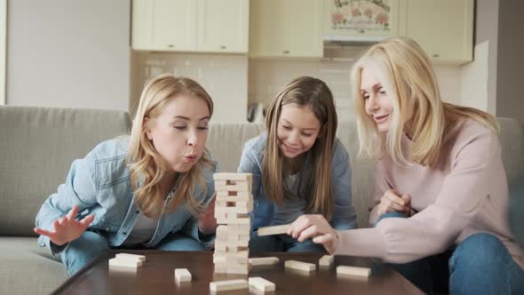 Three Generations of Women Playing Stack and Crash Board Game Together Smiling Young Woman with alt