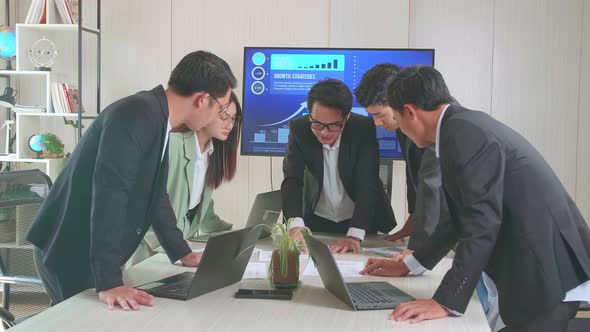 In The Meeting Room Asian Businesspeople Standing Around Table Having Strategic Planning Session alt