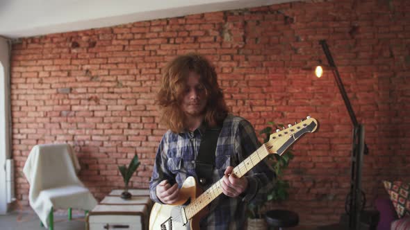 Portrait of Young Man Musician with Long Red Hair Playing Electric Guitar at Home Slow Motion alt