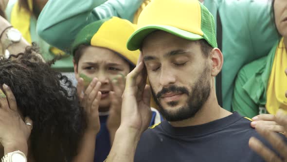 Brazilian soccer fans watching match at stadium with look of disappointment