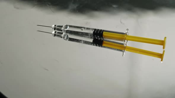 Syringe with vaccine on a bright reflecting backgroun