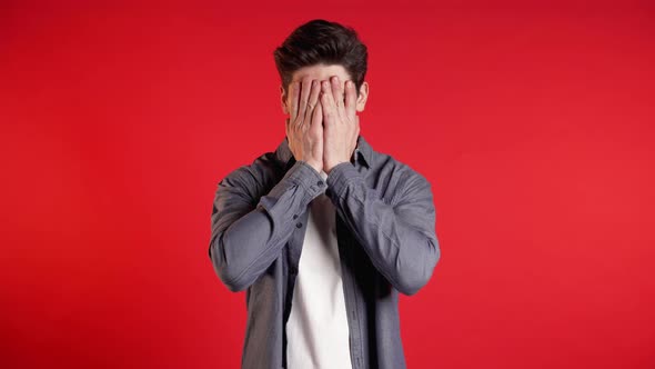 Young Guy Covers His Face with Hands From Fatal Disappointment, Failure.  alt