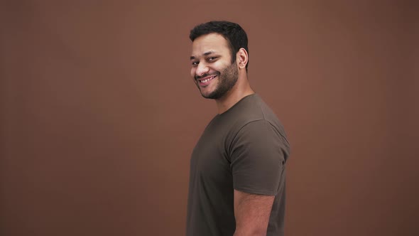 Playful Indian Man Flirting Pointing to Camera with Both Hands and Winking Brown Studio Background alt