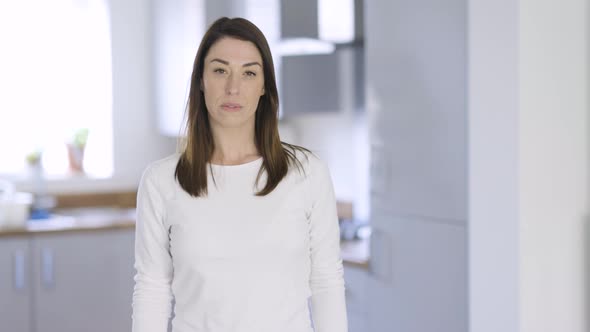 Confident housewife standing at home with arms crossed alt