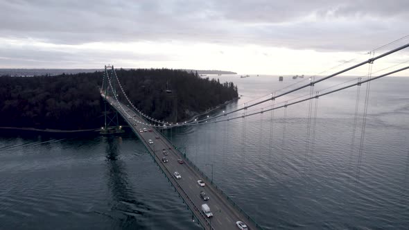 Vehicles driving on Lions Gate Bridge crossing Burrard Inlet fjord, Vancouver in Canada. Aerial forw alt