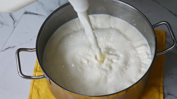 Pouring Milk From Jug Into a Saucepan 