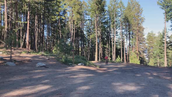 Caucasian man riding a mountain bike up a slope on a curve in Ashland, Oregon alt