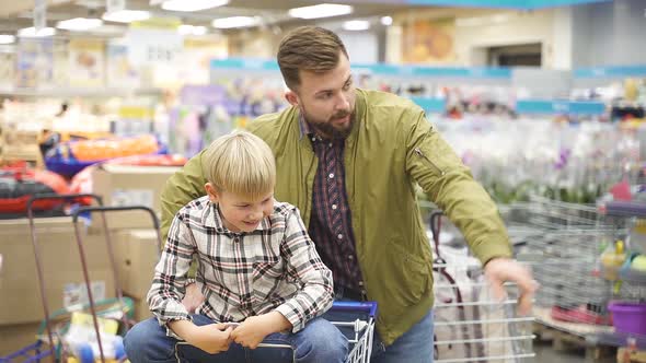 Positive Child Boy Enjoys Shopping Time with Father in Supermarket