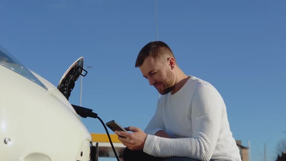 A Male Driver Connects an Electric Car to the Power System to Charge the Car Battery and Controls alt