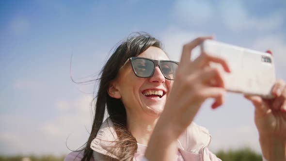 Happy Young Woman Taking Photo on Smartphone and Laughing alt