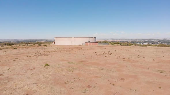 DRONE Reveal Shot of Water Supply Tank supplying water to a Town in the Background on a Sunny Day alt