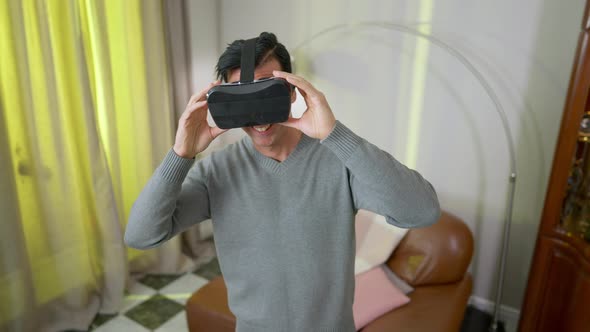 Happy Smiling Middle Eastern Man in VR Headset Standing in Living Room at Home alt