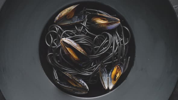 Close Up of Delicious Black Spaghetti Pasta Served with Mussels in Dark Plate alt