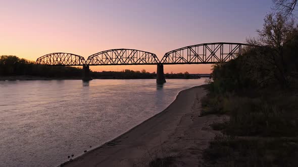 Aerial view flying up the shoreline of the Missouri River toward bridge alt