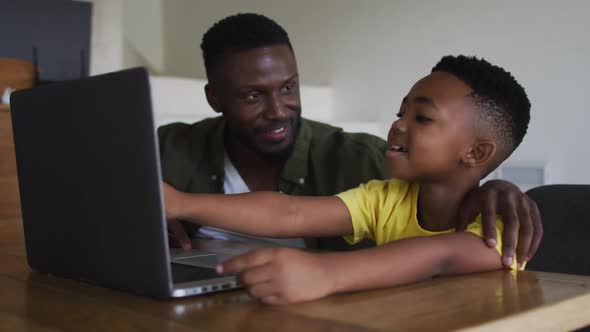 African american father and son using a laptop together alt